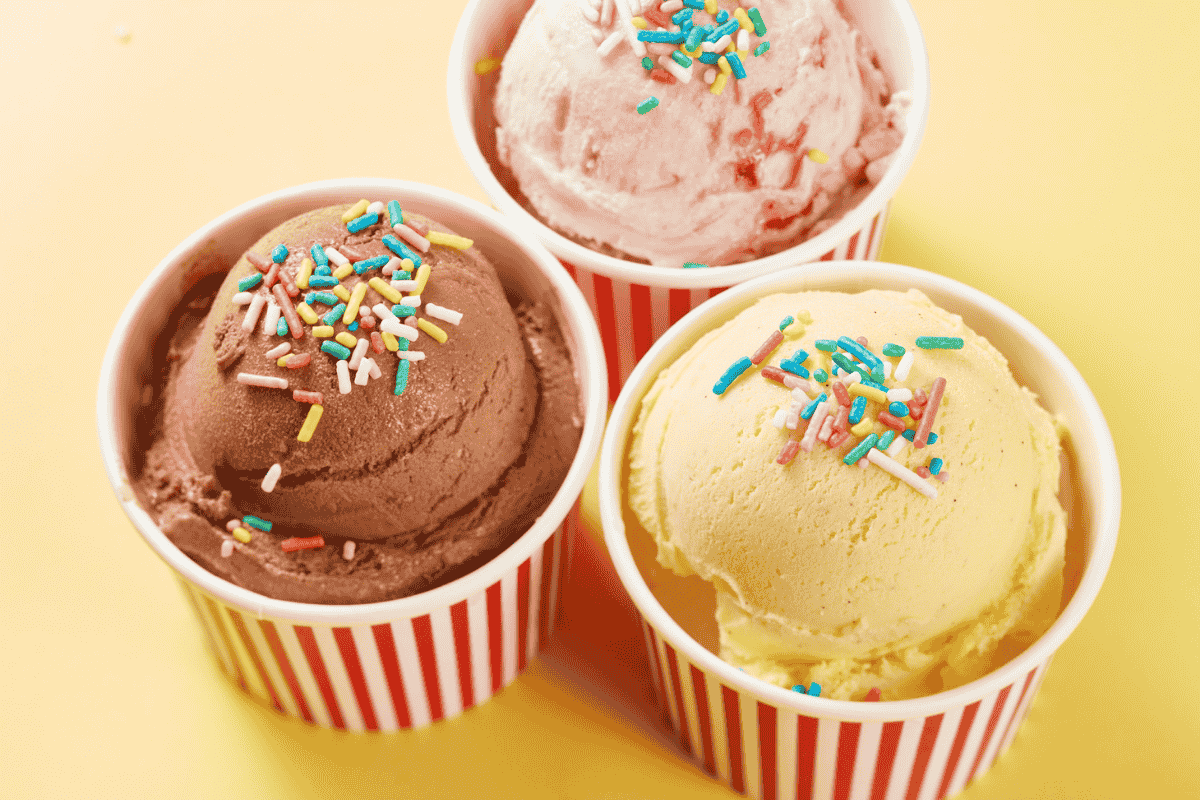 Three featured cups of ice cream—chocolate, strawberry, and vanilla—topped with colorful sprinkles on a yellow background.