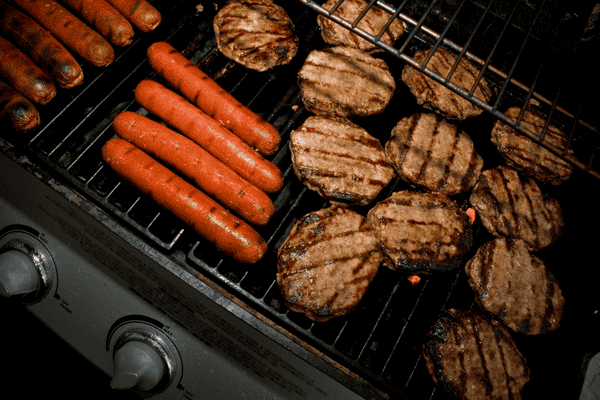 Grilled burgers and hot dogs on a barbecue grill, showcasing perfectly charred patties and sausages, ideal for a summer cookout or backyard barbecue.